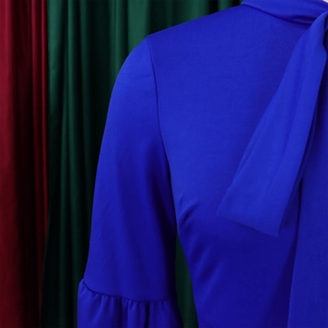Detail of royal blue high neck tie collar and ruffled cuffs on long dress
