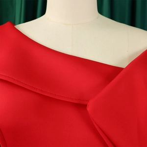 Dettaglio del vestito in raso rosso con scollo asimmetrico e drappeggio sulla spalla