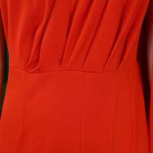 Detail of elegant red jumpsuit showing waist pleated design and smooth stitching texture