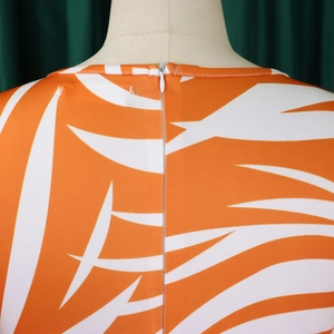 Détail de la fermeture éclair invisible et de l'imprimé feuille orange sur la robe