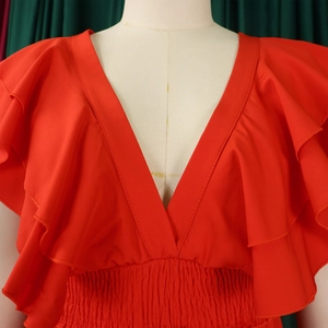 Détail d'une combinaison rouge avec décolleté en V profond, volants et taille élastique