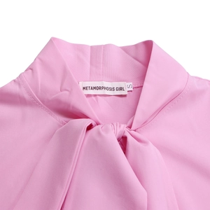 Detail of pink blouse collar with elegant bow tie and brand label on white background