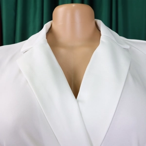 Detail of elegant white sleeveless jumpsuit featuring a sharp notched lapel and V-neckline