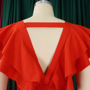 Détail d'une combinaison rouge à col en V profond avec manches volantées et taille élastique