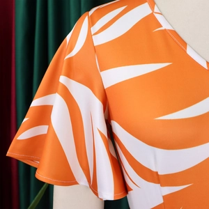 Détail du col rond et des manches à volants sur une robe d'été orange à fleurs