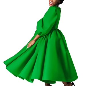Detail of a bright green midi dress featuring dramatic puff sleeves and satin finish fabric