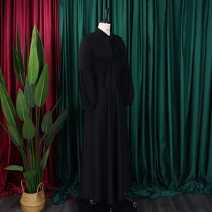 Detail view of black floor-length dress with bow tie collar and puffy lantern sleeves