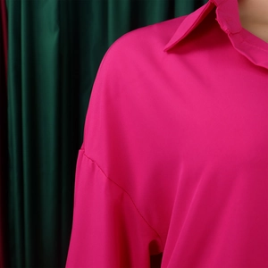 Detail of the rose red long-sleeve shirt showing the collar and shoulder stitching