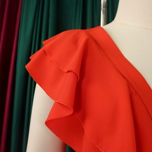 Détail de la combinaison rouge à col en V avec manches à volants et finitions soignées
