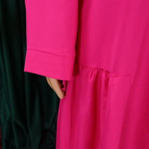 Detailed view of magenta long sleeve cuff and gathered pleat texture on dress