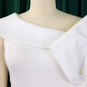 Dettaglio dell'abito bianco con colletto asimmetrico a pieghe e trama in twill pregiato