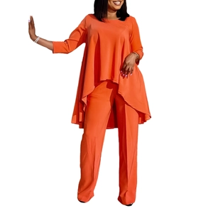 Close-up of bright orange two-piece set featuring asymmetrical hem and wide-leg pants