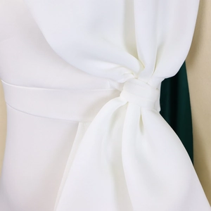 Dettaglio di un abito da sera bianco con pieghe in vita e design decorativo a nodo