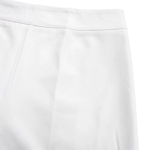 Détail du pantalon large blanc tissé montrant des plis marqués et la texture du tissu