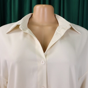 Detailed view of beige button-down collar and lightweight woven fabric on loose dress