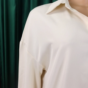 Detail view of cream long sleeve dress featuring soft silky fabric and lapel collar