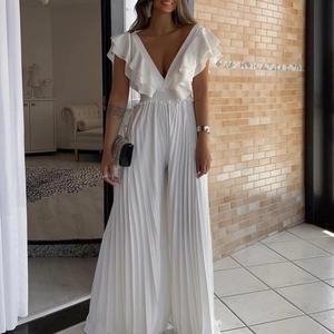 Détail d'une combinaison blanche à col en V profond avec volants et pantalon large plissé