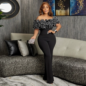 Detail of elegant black off-shoulder jumpsuit featuring bold white ruffles and high waist