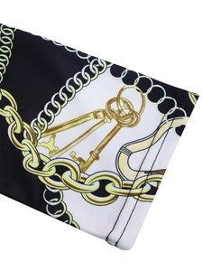 Detail of elegant black and white floral dress with golden chain and key print patterns