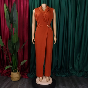 Detail eines orangefarbenen ärmellosen Jumpsuits mit Reverskragen und goldener Kette