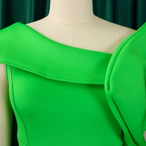 Dettaglio dell'abito verde brillante con scollatura asimmetrica e volant a strati