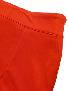 Detail of orange high-waisted trousers featuring double stitching and a side zipper