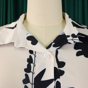 Détail d'un col de chemise avec imprimé botanique monochrome et bouton blanc arrondi