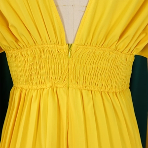 Détail macro du combishort jaune à col en V avec taille smokée et plis élégants