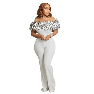 Detail of ruffled off-shoulder neckline with black trim on white wide-leg jumpsuit
