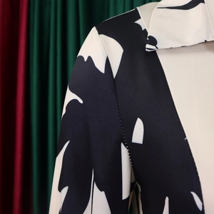 Gros plan du col à revers et de l'imprimé feuilles noir et blanc sur une robe d'été