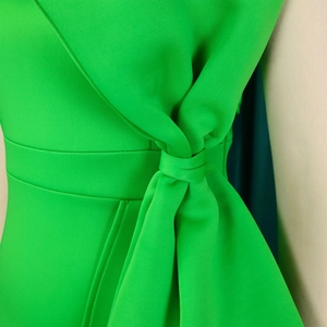 Dettaglio del nodo decorativo verde lime e cuciture di qualità sull'abito da sera aderente