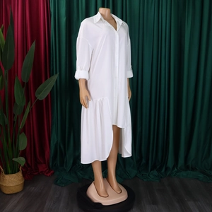 Detail view of high-low asymmetric hem with ruffled edge on white long sleeve shirt dress