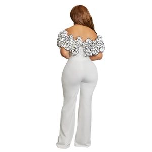 Detail of white off-shoulder jumpsuit with ruffled floral accents and black edge stitching