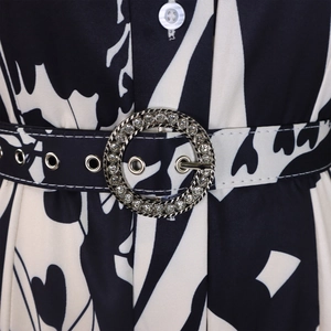 Détail de robe imprimée avec ceinture noire ornée d'une boucle ronde sertie de cristaux