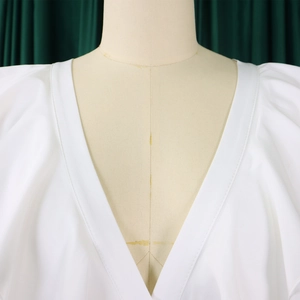 Détail d'une combinaison blanche à décolleté en V profond avec volants et manches structurées