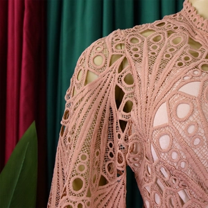 Detailed close-up of pink geometric lace embroidery and hollow out crochet texture