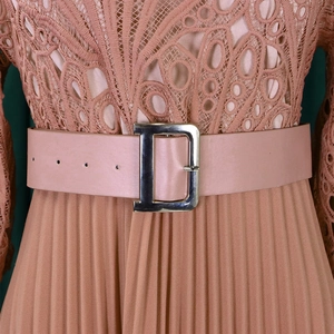 Close-up of a wide pink leather belt with a large silver D-shaped buckle on a dress