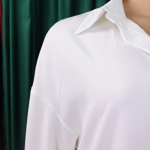 Close-up of bright white loose-fit shirt showing classic sharp collar and shoulder seams