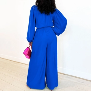 Back view of a long-sleeved royal blue wide-leg jumpsuit with high elastic waist detail