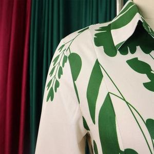 Détail du col à revers élégant et imprimé de feuilles vertes sur une robe d'été blanche