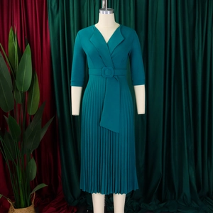 Détail d'une robe plissée sarcelle avec décolleté en V, ceinture assortie et jupe accordéon