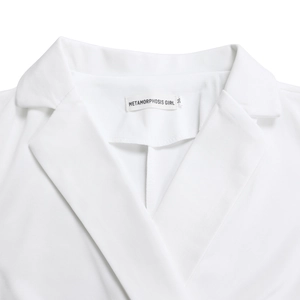 Detailed view of white sleeveless jumpsuit collar with brand label and fabric texture