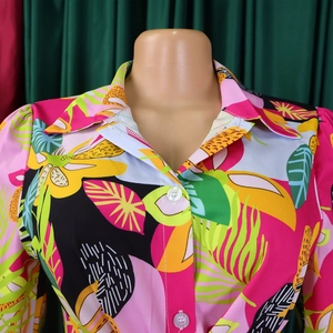 Gros plan sur l'imprimé feuilles tropicales, col à revers et boutons blancs de la chemise