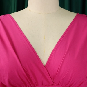 Détail du décolleté en V profond et des plis sur une combinaison pantalon rose