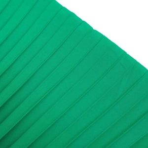 Gros plan sur la texture du tissu plissé vert vif de cette combinaison à jambes larges