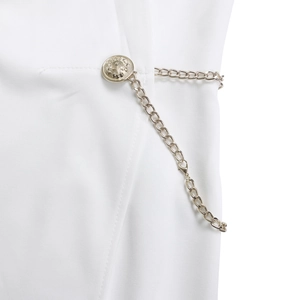 Macro detail of elegant golden embossed button and metal chain on white woven fabric