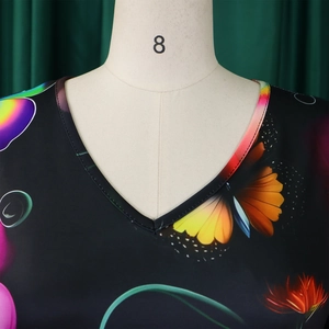 Détail du décolleté en V sur une robe noire avec imprimé floral et papillons