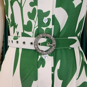 Détail de robe imprimé feuilles vertes avec ceinture à boucle en strass et boutons blancs