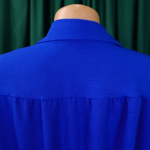 Detail view of royal blue long sleeve jumpsuit showing back yoke and pleated fabric texture