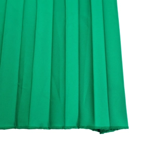 Détail du tissu plissé vert vif montrant des plis verticaux et une fine couture overlock